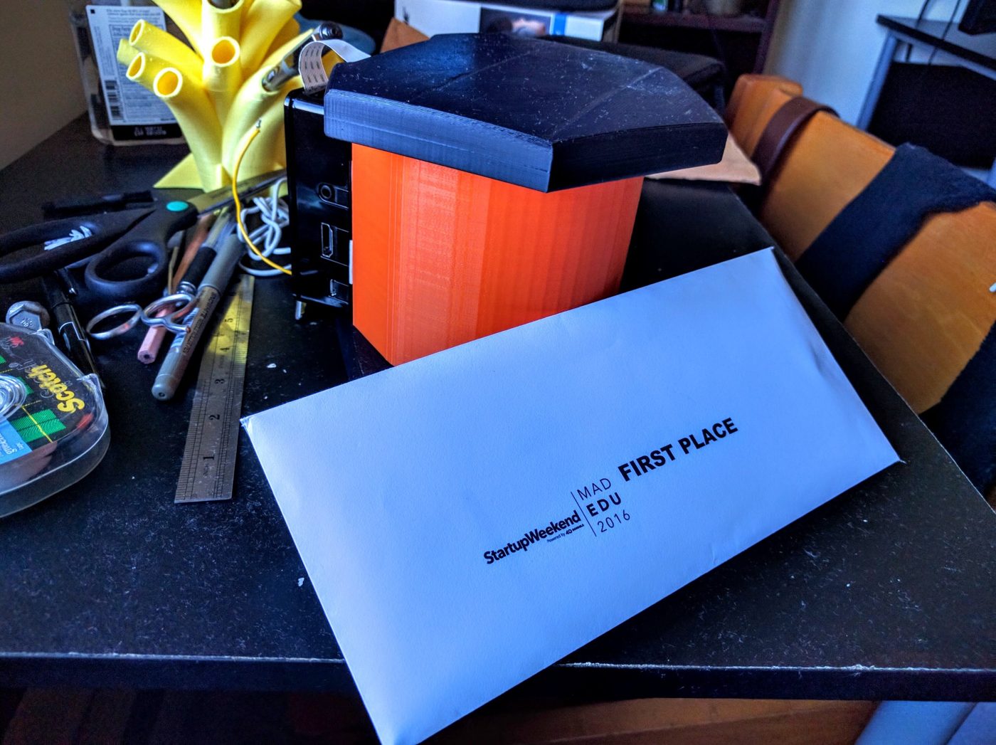 The first FlashLapse, a 3D-printed time-lapse imaging chamber, beside the first-place envelope from Startup Weekend Madison EDU 2016